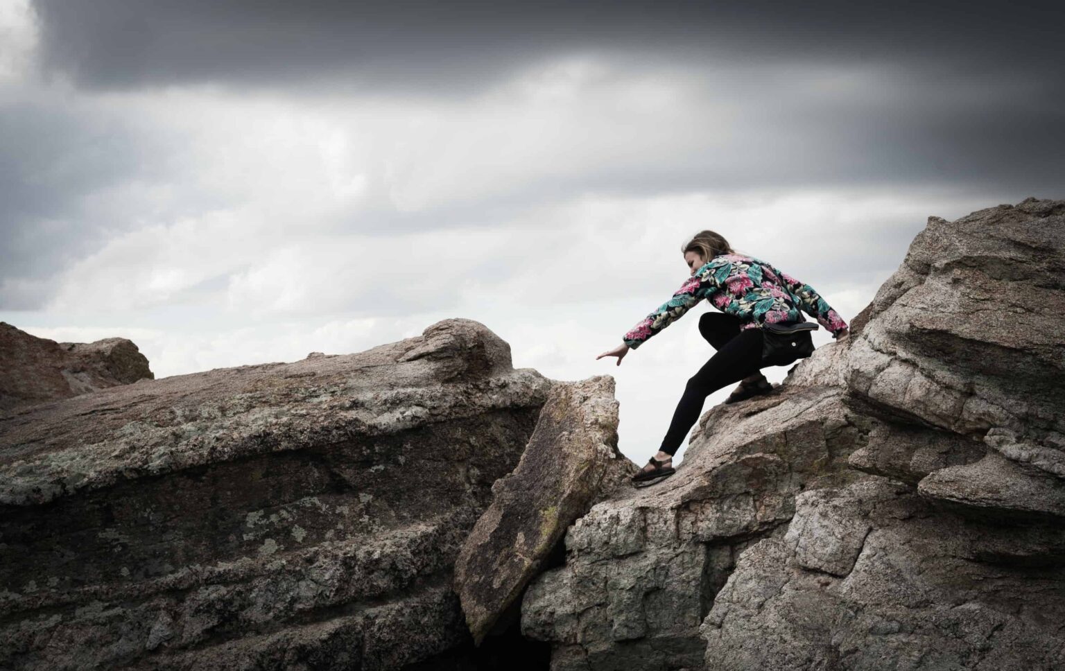 mujer fotografiada mientras trepa por las rocas durante el día